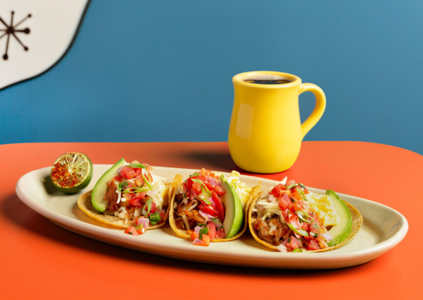Snooze's Breakfast Tacos with Lime & Coffe On An Orange Tabletop